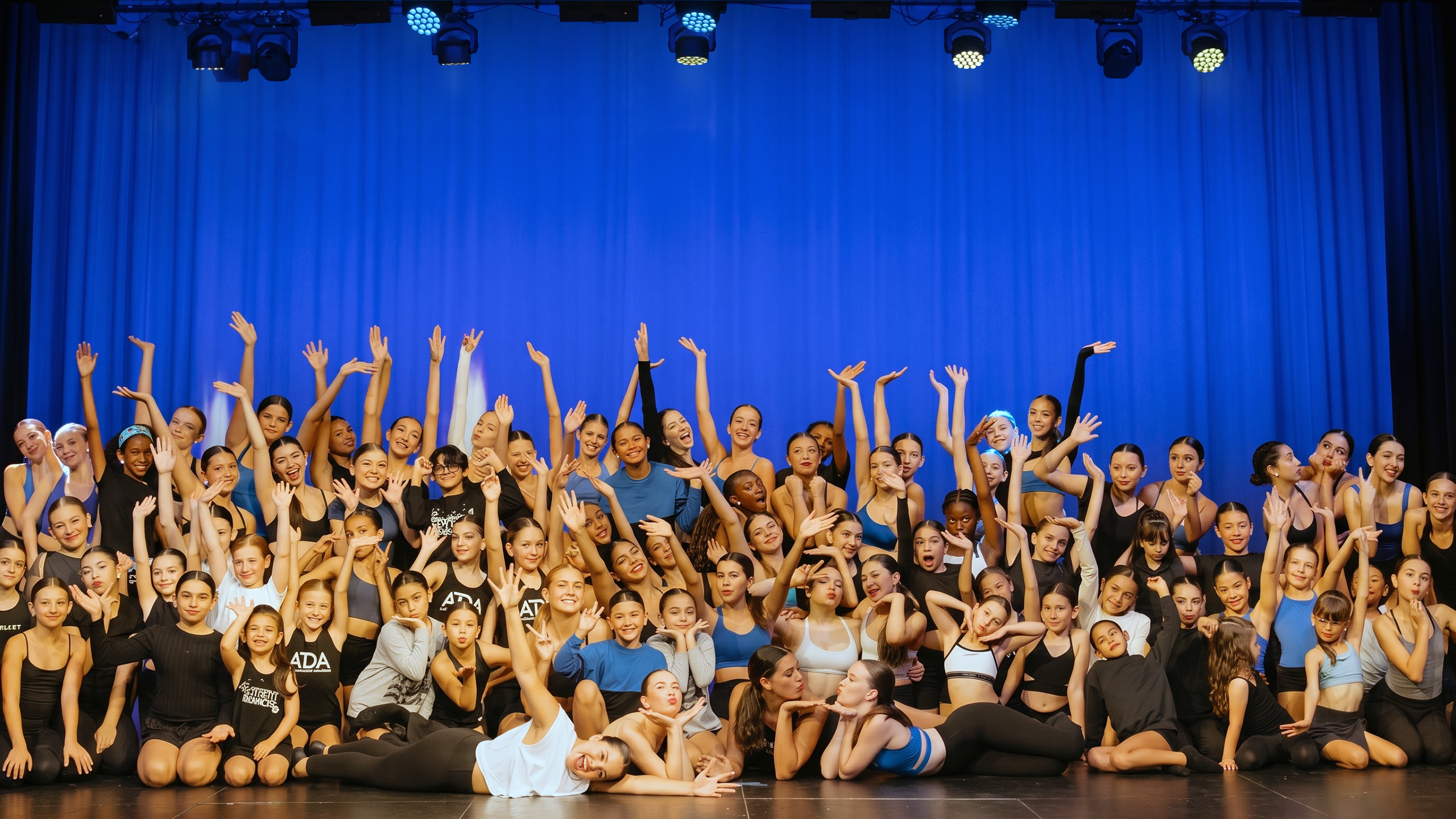 Artistic Dance Academy students of different ages pose together on stage, showing an inclusive community united by their passion for dance.